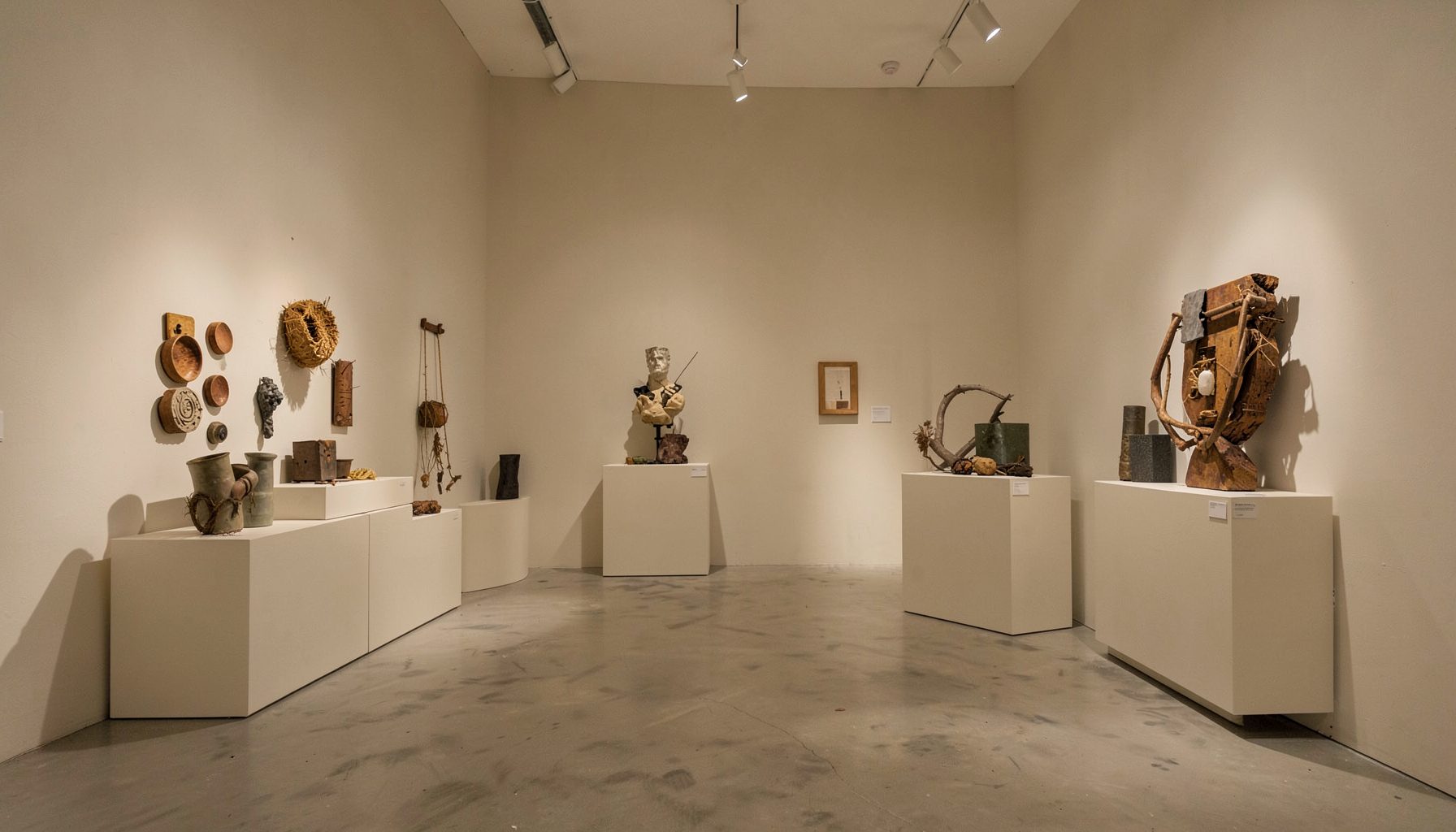 Minimal gallery interior with sculptural works incorporating found objects and everyday materials in a neutral palette
